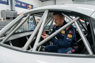 Mécanicien inspectant la cage de sécurité d'une Porsche GT3 Cup dans un garage de paddock professionnel