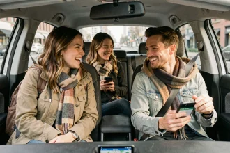 Trois covoitureurs urbains partageant un trajet en voiture compacte, regardant une application de covoiturage sur smartphone