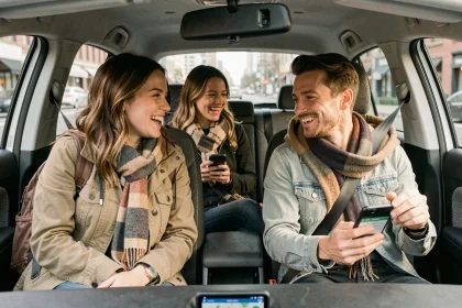 Trois covoitureurs urbains partageant un trajet en voiture compacte, regardant une application de covoiturage sur smartphone