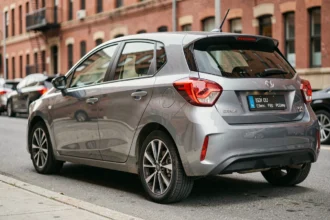 Voiture compacte moderne de 81 kW garée en ville, vue en perspective 3/4 arrière mettant en valeur la carrosserie et les jantes