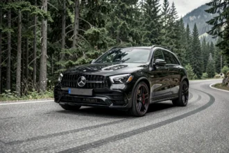 Mercedes-AMG GLC 63 S en noir obsidienne dans un virage de route de montagne, vue trois-quarts avant, détails AMG en netteté